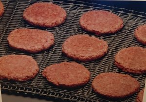 Raw hamburgers on the Stainless Steel Mesh Overlay Belt of an IJ White Spiral Freezer