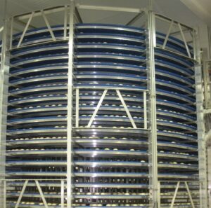 Spiral Cooler with Rolls placed on a Blue Plastic Conveyor Belt
